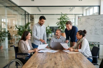 Équipe diversifiée de collègues de différentes origines et âges travaillant ensemble autour d'une table de réunion dans un bureau moderne inclusif